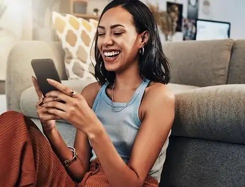 A creator smiling while checking a message at home