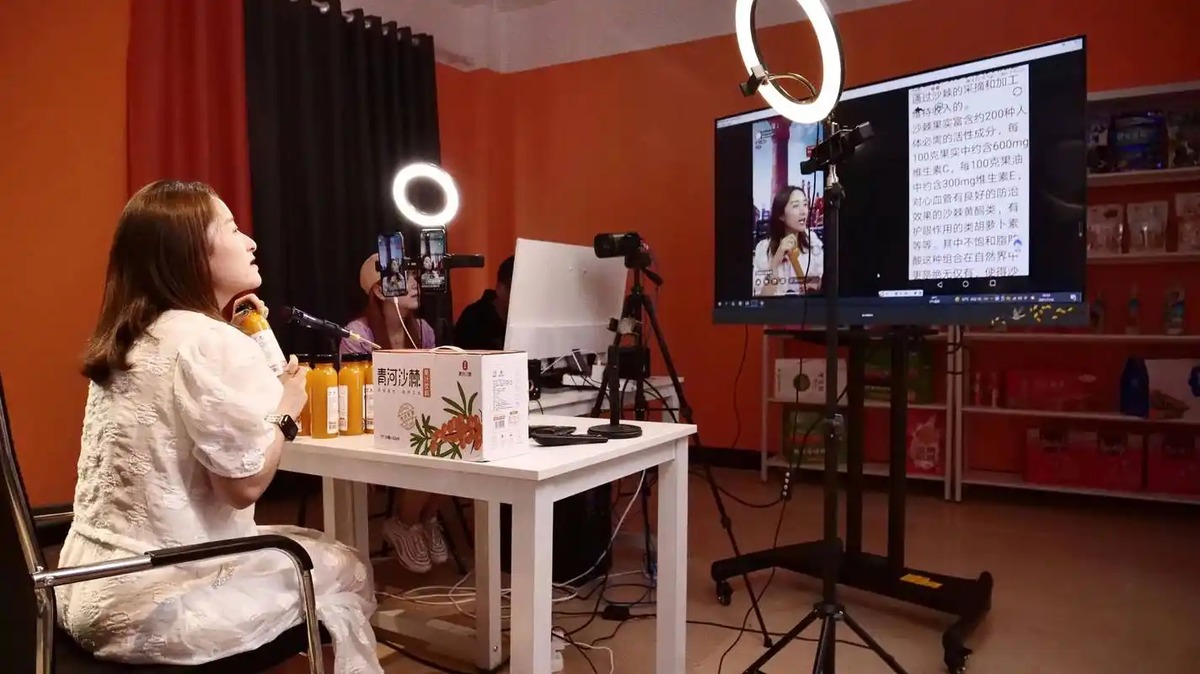 Presenter di meja dengan monitor dan ring light di studio konten